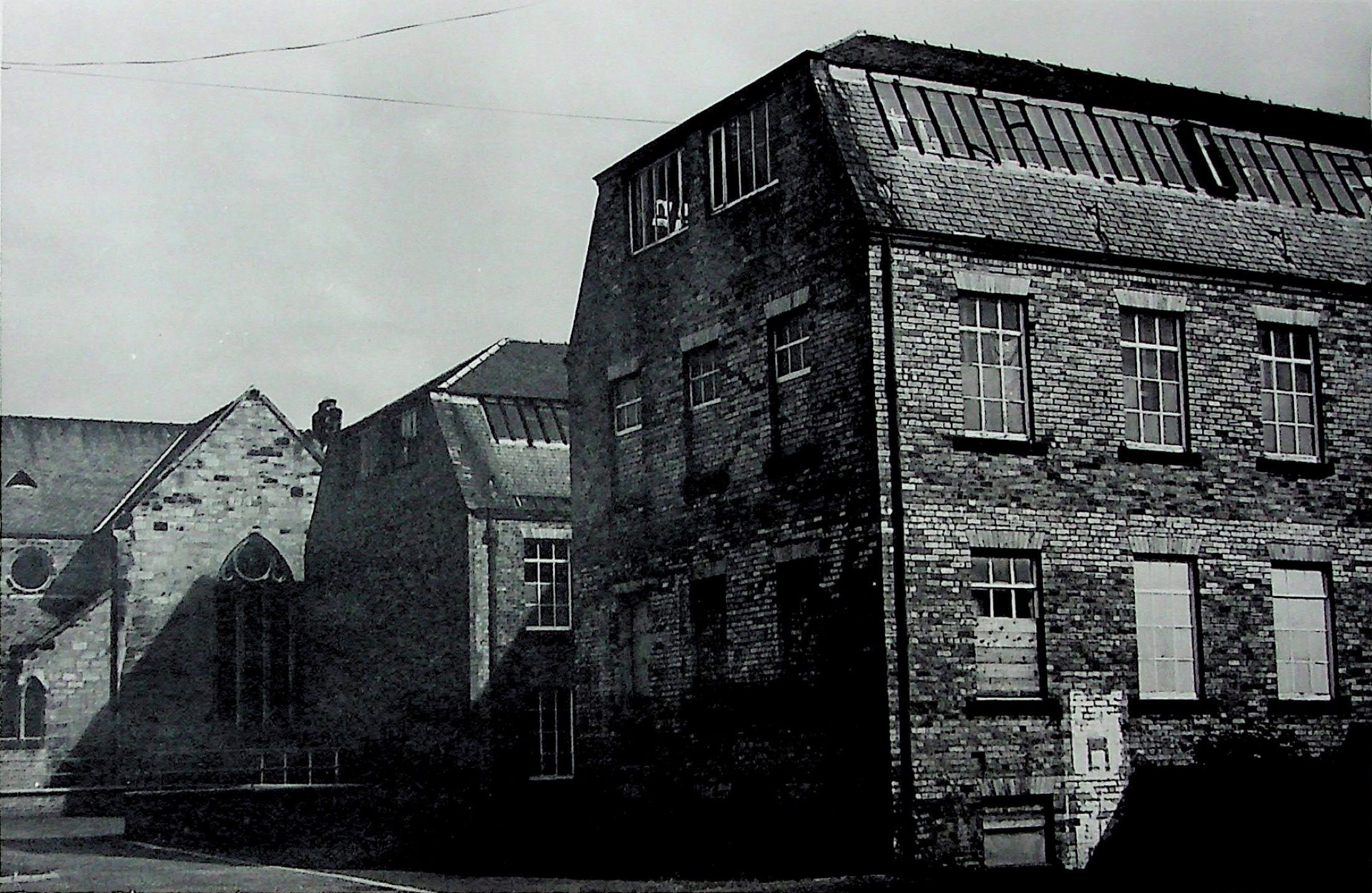 Tall brick buildings of the Alexander Morton factory beside a church